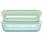 Two glass food storage containers with green and blue lids on a white background