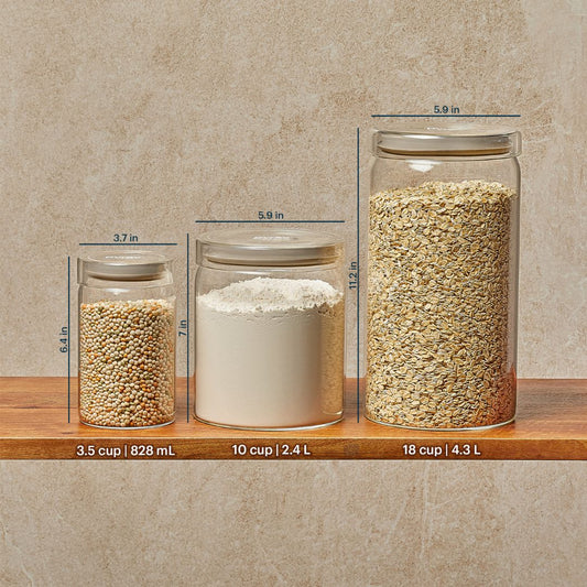 Three glass jars with different contents and measurements on a wooden shelf against a beige wall.