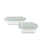 Two glass food storage containers with green lids on a white background