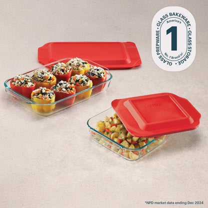 Glass bakeware set with red lids on a beige surface, featuring Pyrex branding.